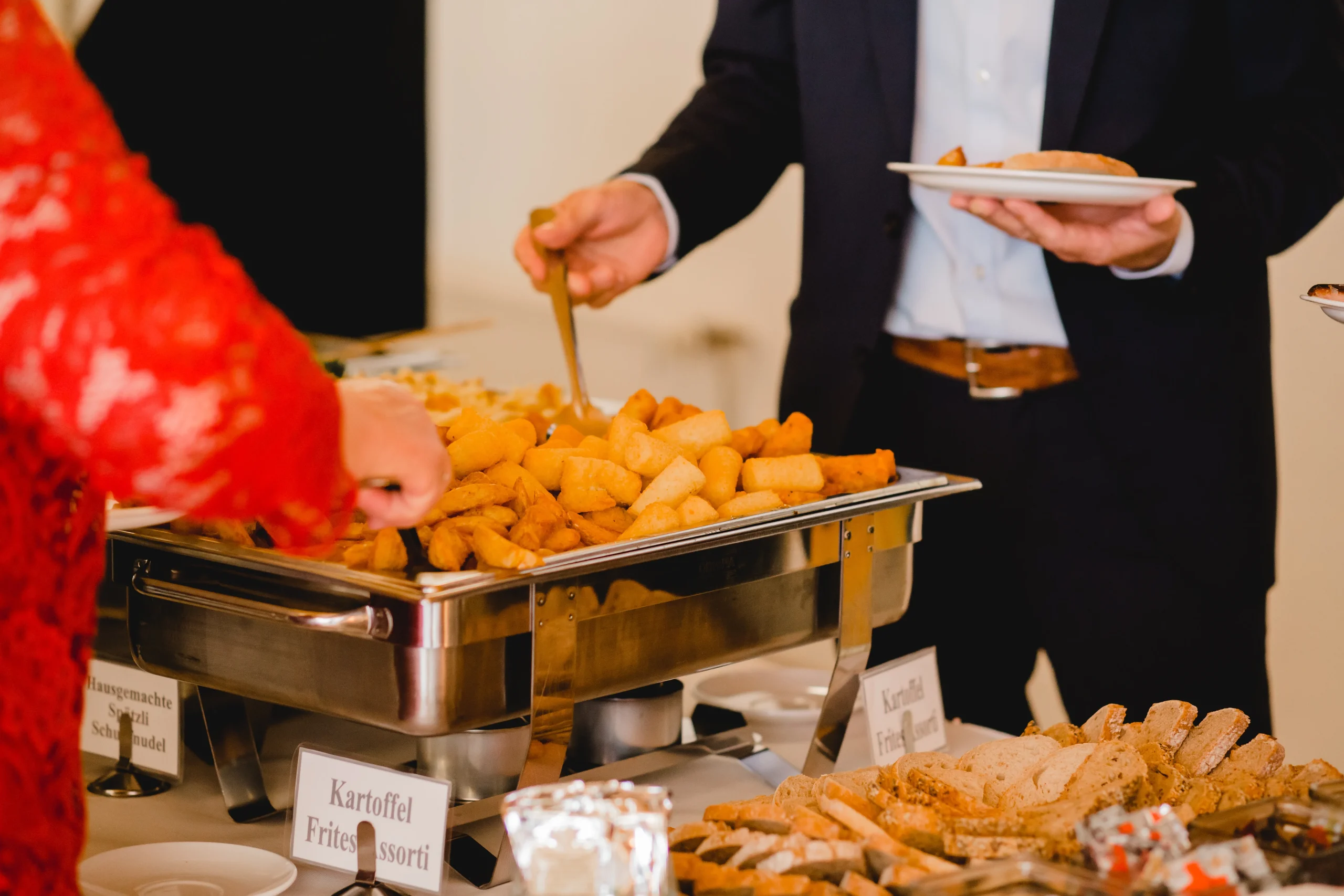 People serving from buffet with fries assortment.