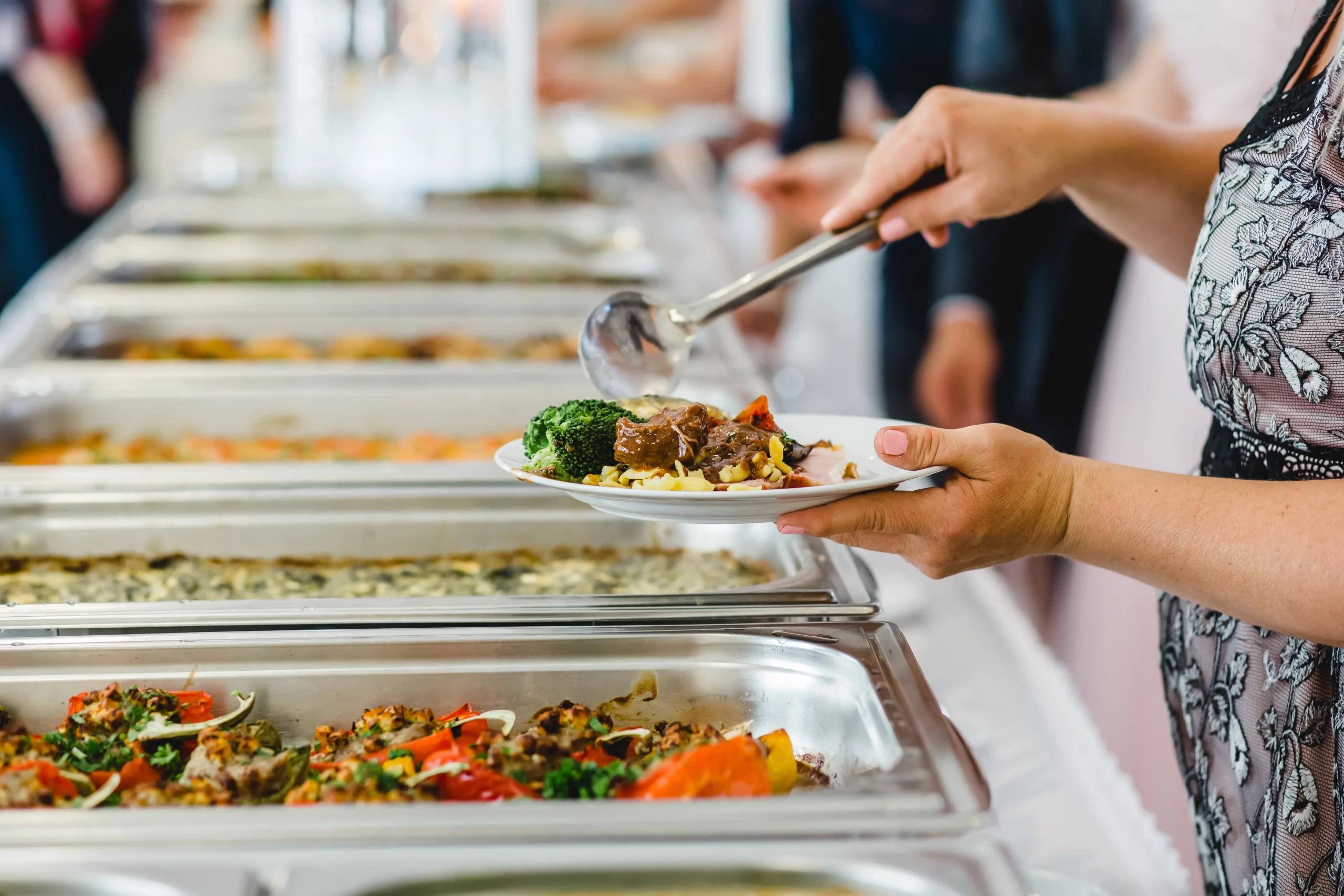 Person serving food at a buffet table.